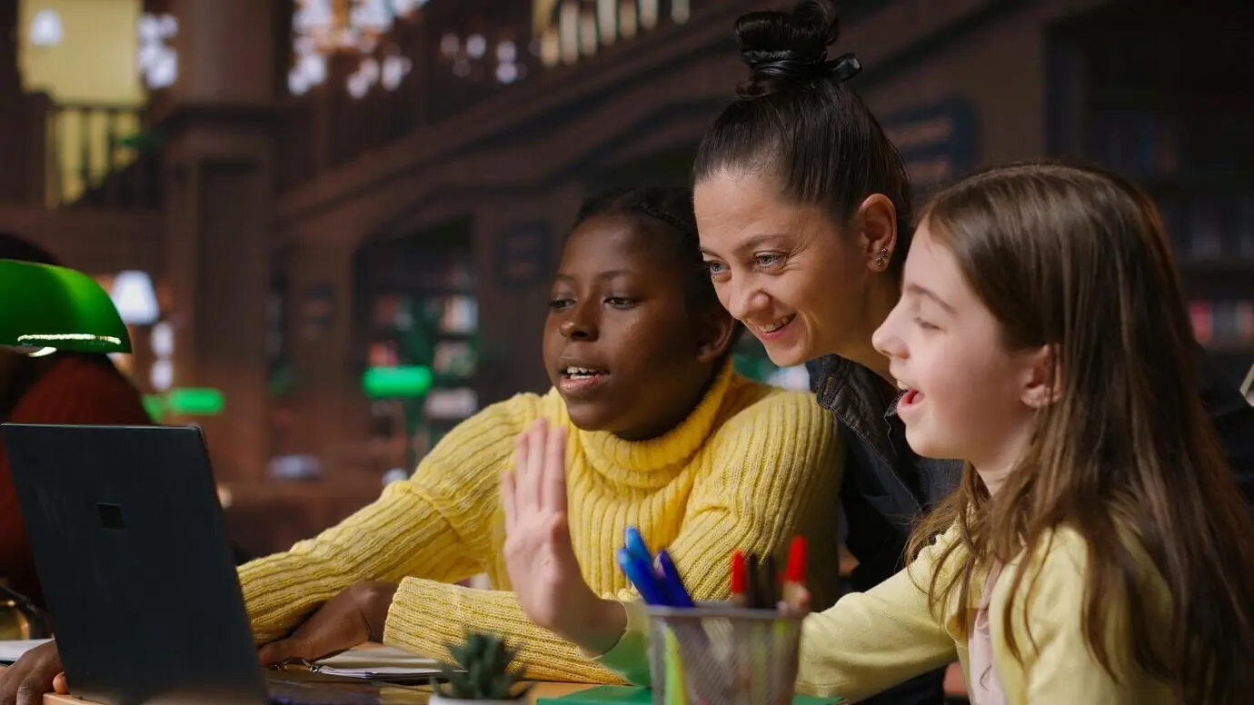 Studierende unterschiedlicher ethnischer Herkunft in der Bibliothek beim Fernlernen mit ihrem Mentor.